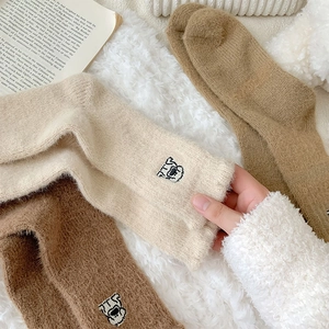 Detail of plush thermal winter socks featuring cute cartoon bear embroidery and soft texture