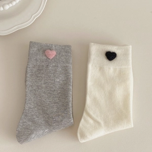 Detail of gray and off-white crew socks featuring small heart embroidery accents