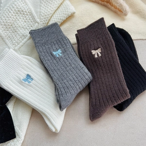 Détail de chaussettes en maille avec broderie de rubans en quatre couleurs douces