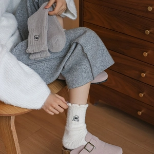 Close-up of warm fleece socks featuring cute dog embroidery and frilly lettuce edges
