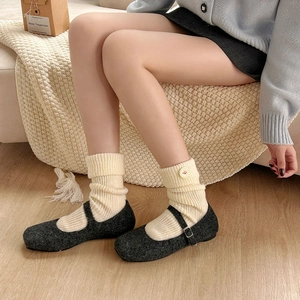 Cream knit slouch socks with buttons and grey Mary Jane wool shoes in home setting