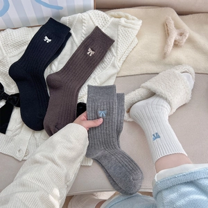 Détail de chaussettes en tricot avec broderie nœud en noir, marron, gris et blanc