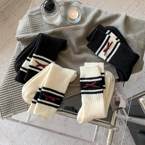 Close-up of thick knitted wool socks with striped trim and red bow detail for winter