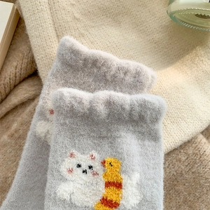 Dettaglio di calze di peluche grigio chiaro con ricami di gatti e pulcini carini