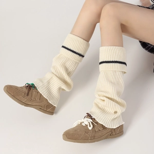 Close-up of cream ribbed knit leg warmers with black stripe detail and soft texture