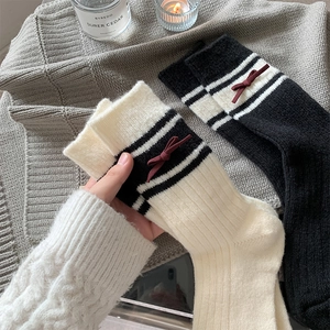 Close-up of knit wool socks with red bow detail and stripes in a cozy lifestyle setting