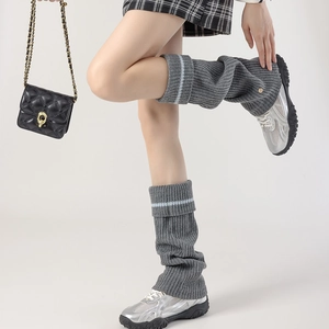 Close-up of grey knit leg warmers with blue stripes and a small gold buckle detail