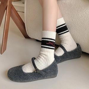 Close-up of white knitted socks with red bow detail paired with grey Mary Jane shoes