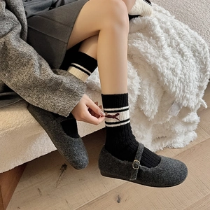 Detail of wool Mary Jane shoes with black bow striped mid-calf socks for autumn and winter