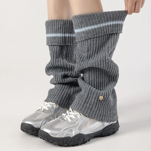 Detail of grey knitted leg warmers with blue stripes and decorative gold metal buckle