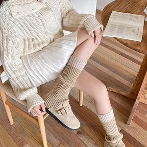 Dettaglio di scaldamuscoli in maglia beige e kaki con trama a coste verticali