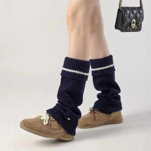 Close-up of navy blue knit leg warmers with white stripe and thick ribbed texture