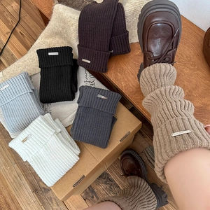 Detail of ribbed knit leg warmers with metal logo labels in multiple winter colors