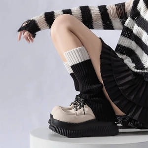 Dettaglio di scaldamuscoli in maglia a righe bianco e nero con mocassini platform
