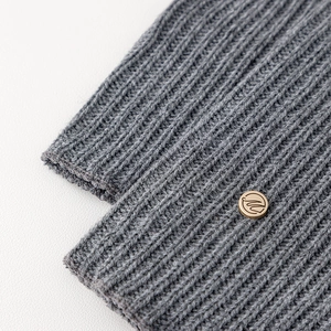 Macro detail of grey ribbed knit leg warmers with an elegant gold metal logo buckle