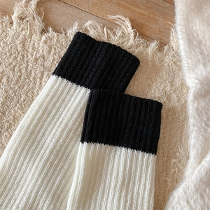Dettaglio degli scaldamuscoli in maglia bianco e nero con morbida trama a coste