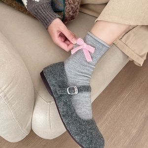 Detail of wool Mary Jane shoes paired with knit socks and pink bow accents