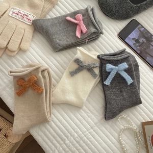 Detailed flat lay of cute knit mid-calf socks with bows and matching gloves in soft colors