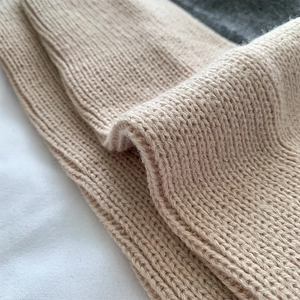 Macro shot of beige ribbed knit leg warmer showing soft texture and warm winter material
