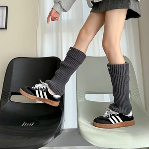 Dark grey knitted leg warmers with vertical ribbing and metal detail shown in lifestyle view