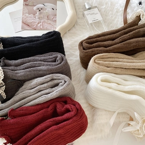 Detailed close-up of knitted leg warmers in various colors with lace and bow details