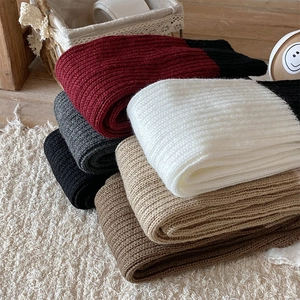 Dettaglio macro di scaldamuscoli in maglia spessa in vari colori su tappeto bianco