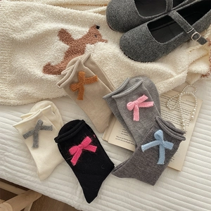 Close-up of ribbed knit socks with bow details and ruffled cuffs in various colors