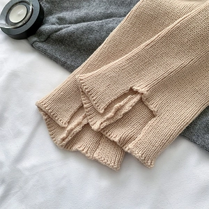 Detailed macro view of beige chunky knit leg warmers showing a stylish split hem design