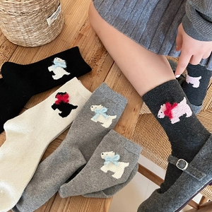 Detail of wool socks featuring plush puppy patterns with decorative 3D bows