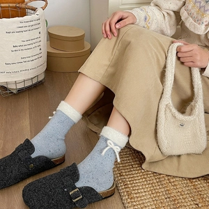 Detail of light blue crew sock with white faux fur trim and delicate bow embellishment