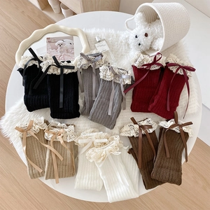 Detailed view of knitted leg warmers with delicate lace trim and silk bow accents