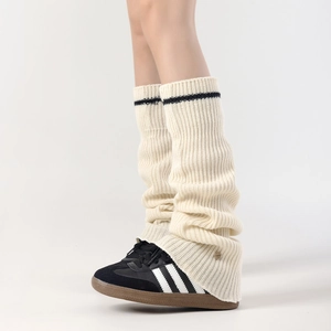 Detail of cream knitted leg warmers with black stripe and metal button embellishment