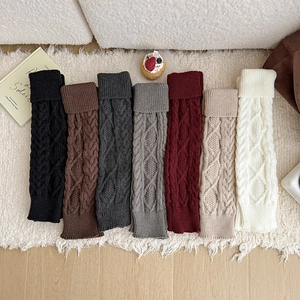 Détail de jambières en maille torsadée multicolore avec revers sur un tapis doux