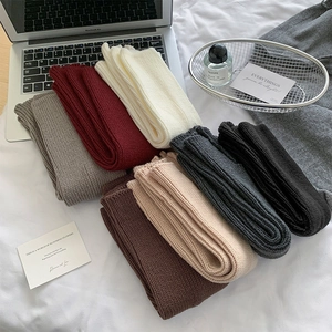 Macro view of thick knit leg warmers in 7 colors on a cozy white bed setting