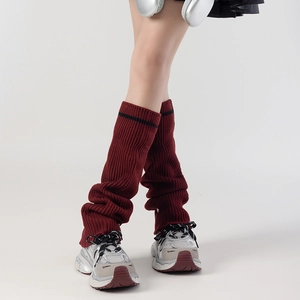 Detail of burgundy ribbed knit leg warmers featuring a black stripe and thick texture