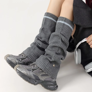 Detail of grey knitted leg warmer with blue stripe and golden metal button accent