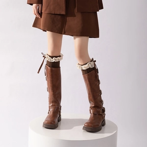 Brown leather boots with lace trim bow leg warmers and metal buckles on white stand
