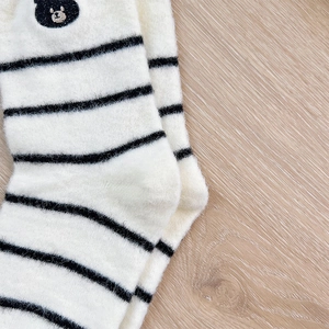 Close-up of thick striped thermal socks with cute bear embroidery on plush fabric