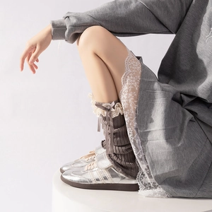 Close-up of grey knitted leg warmers featuring delicate lace trim and a satin bow detail