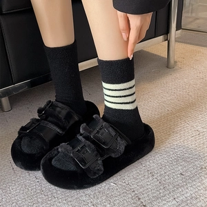 Detailed view of black fuzzy slides with double straps and white striped crew socks