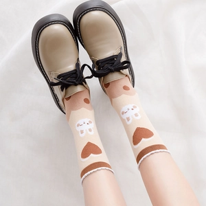 Detail of beige bear socks with heart patterns worn with stylish platform shoes