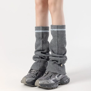 Detail of grey knitted leg warmers featuring vertical ribs and blue stripe accents