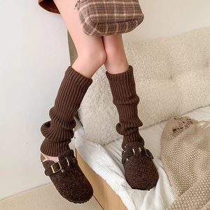 Detailed close-up of brown ribbed knit leg warmers paired with retro wool mule shoes