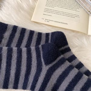 Close-up of blue and grey striped thermal socks on a soft white plush rug background