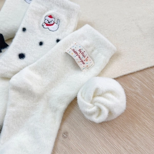 Detail of warm white plush socks featuring cute dog embroidery and holiday gift tags