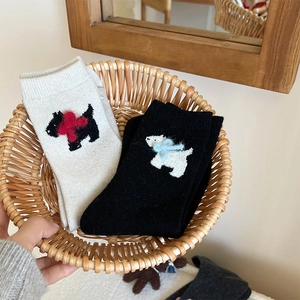 Close-up of wool socks featuring cute dog patterns and bows in a cozy basket