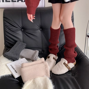 Close-up of ribbed knit leg warmers in burgundy, dark grey, light grey, and cream beige