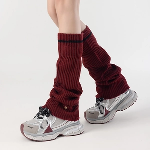 Detail of burgundy knitted leg warmer with ribbed texture and gold metal button decoration