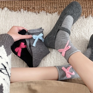 Close-up of soft knitted socks with cute yarn bows in grey and black colors