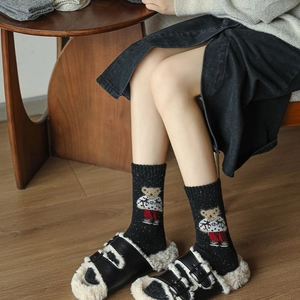 Close-up of black knitted wool socks featuring a cute 3D bear pattern and cozy texture
